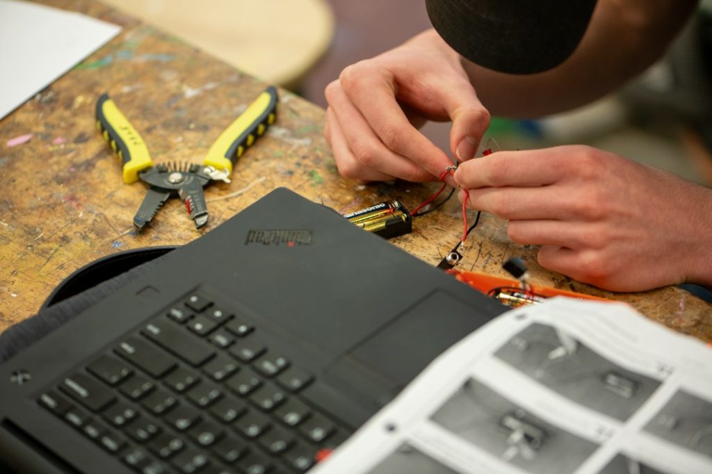 Técnico revisando una laptop y componentes electrónicos en banco de trabajo